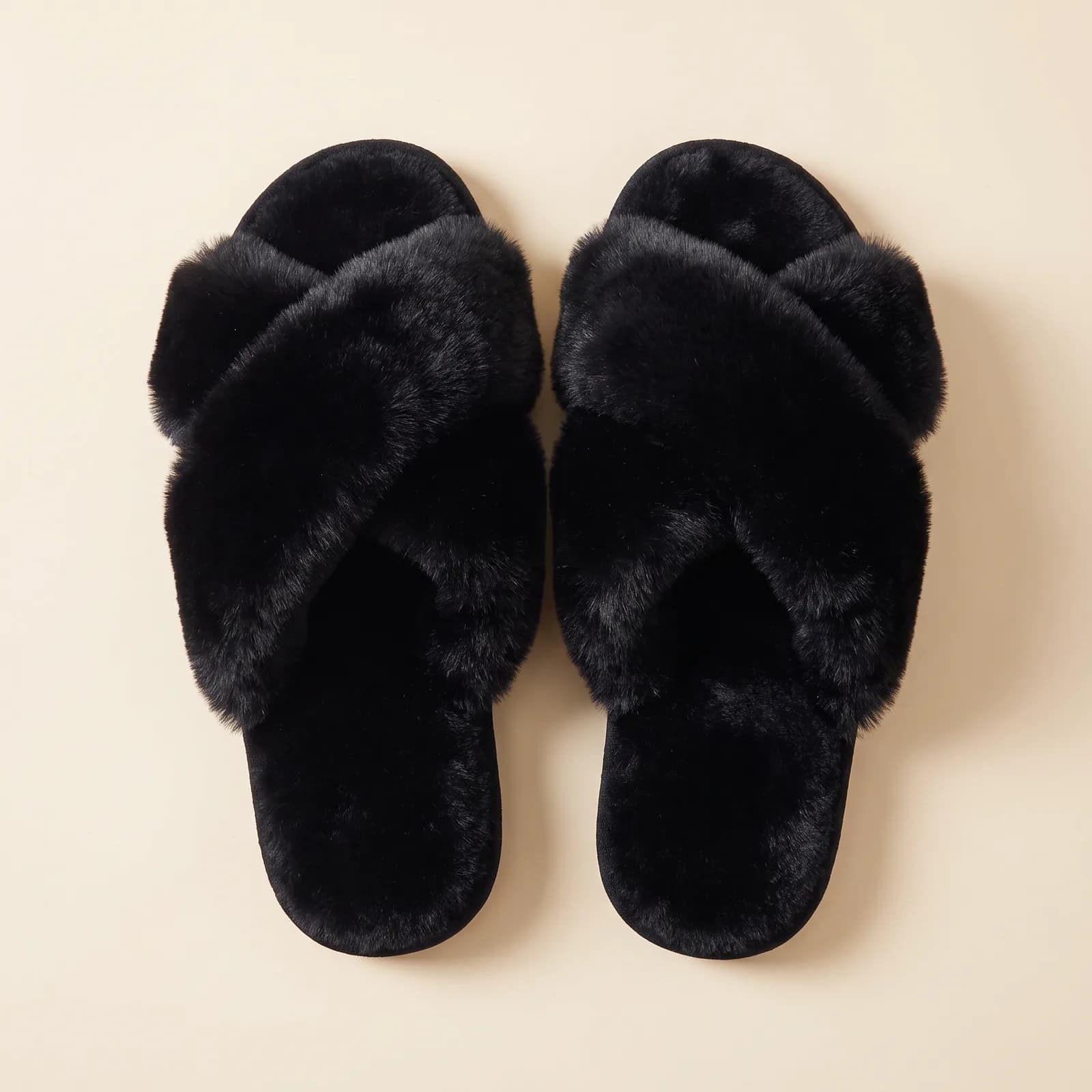 Fuzzy cross-strap slippers on a wood floor