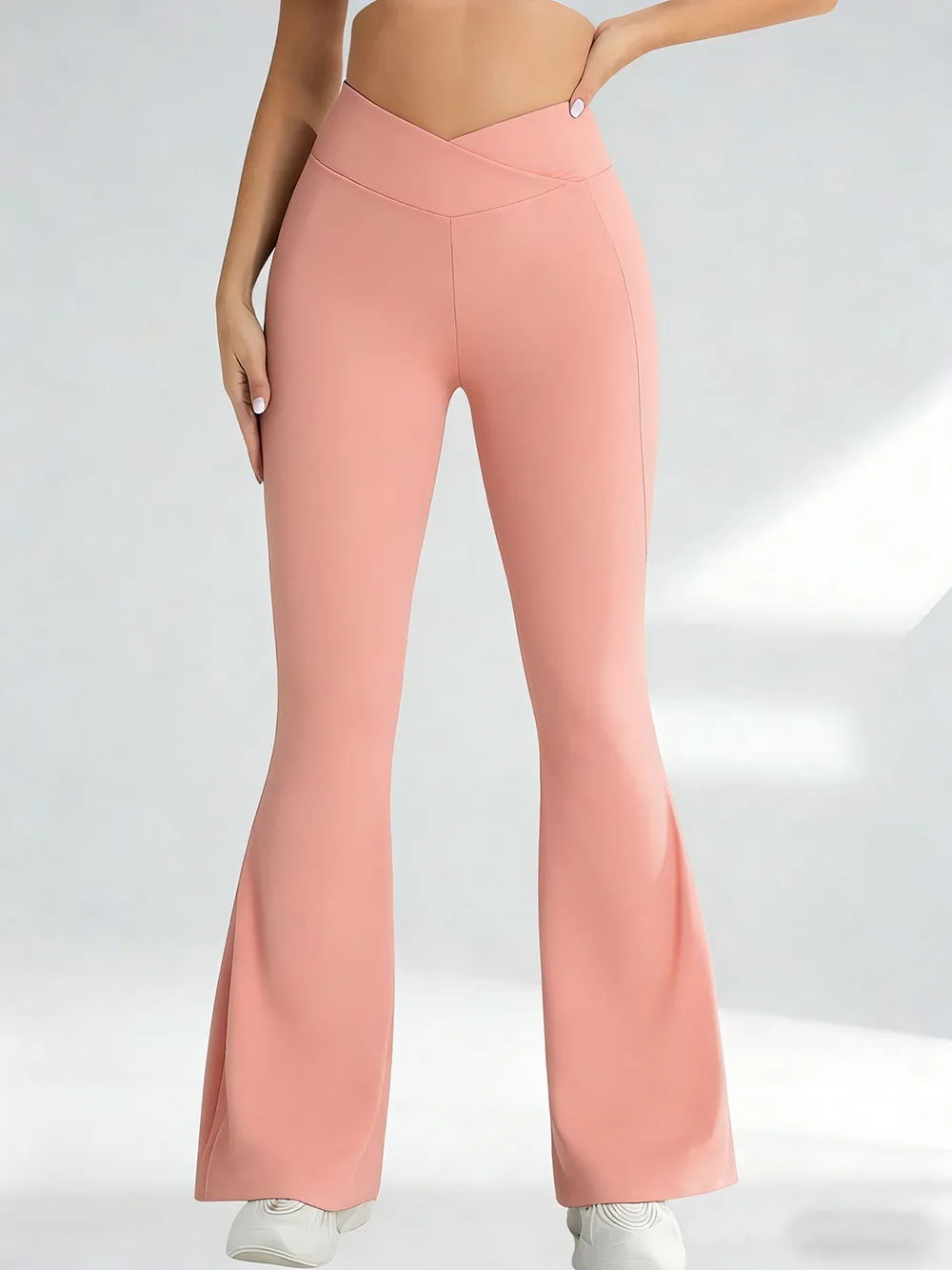 A person wearing peach crossover flare yoga pants against a plain background
