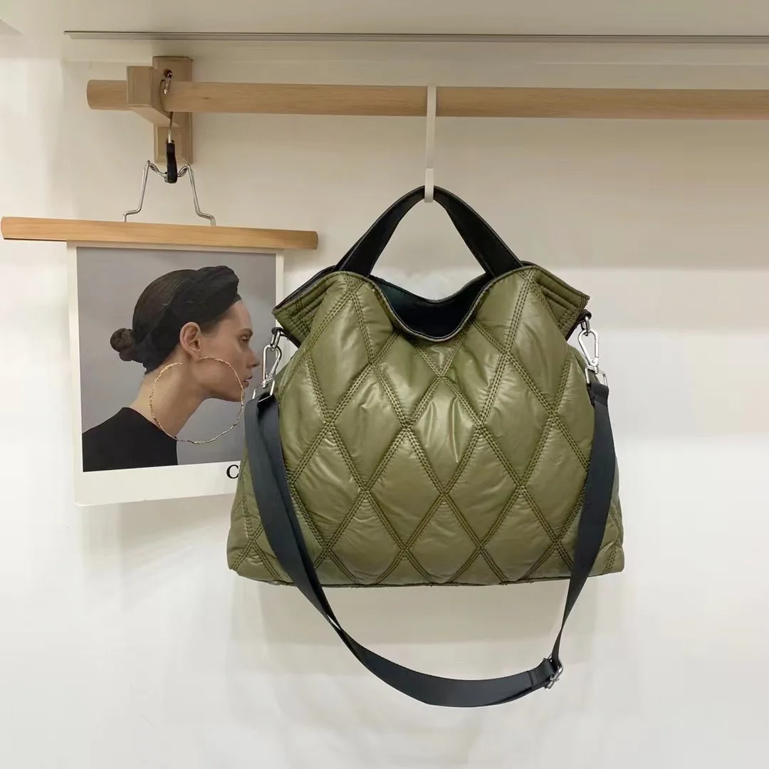 An olive green quilted puffer commuter tote bag hanging from a wooden rack