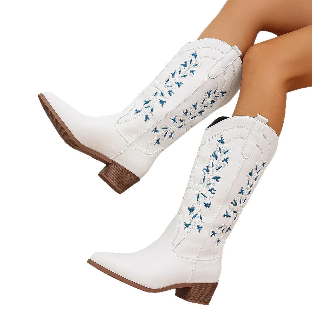 A pair of white western boots with blue embroidery worn on a person's legs against a white background