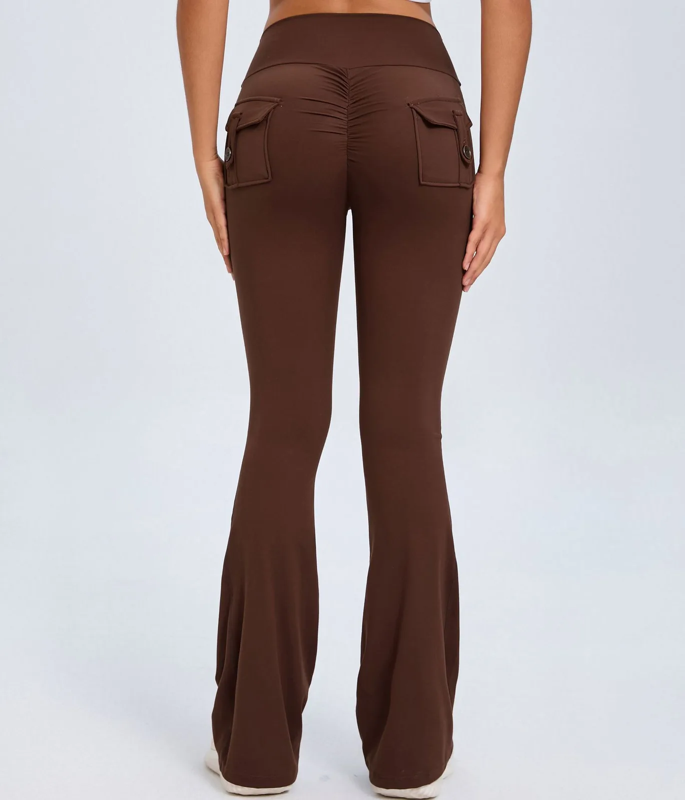 Back view of brown flare leggings with pockets and ruched detailing worn by a model