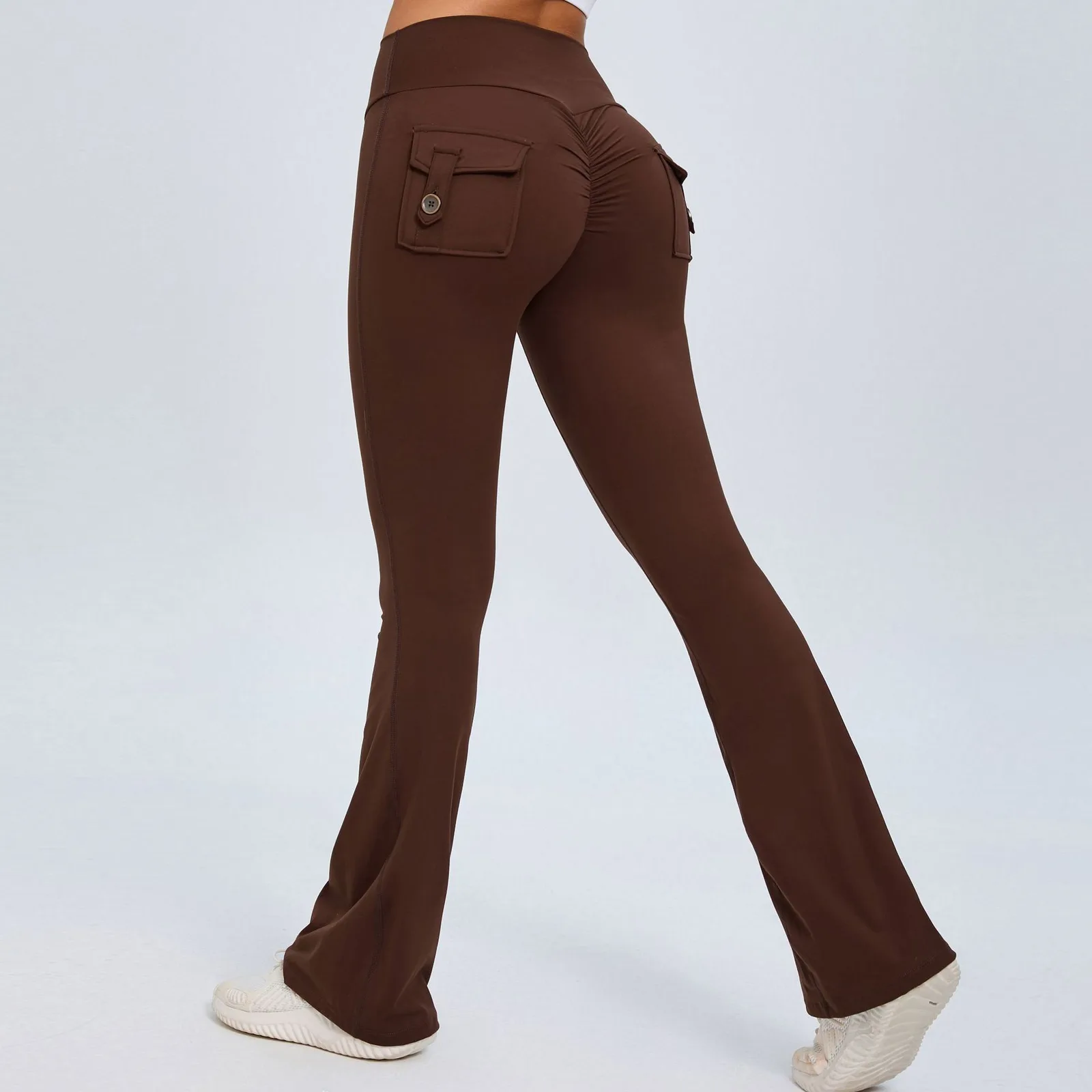 A person wearing brown flare leggings with back pockets and a ruched detail on a plain background