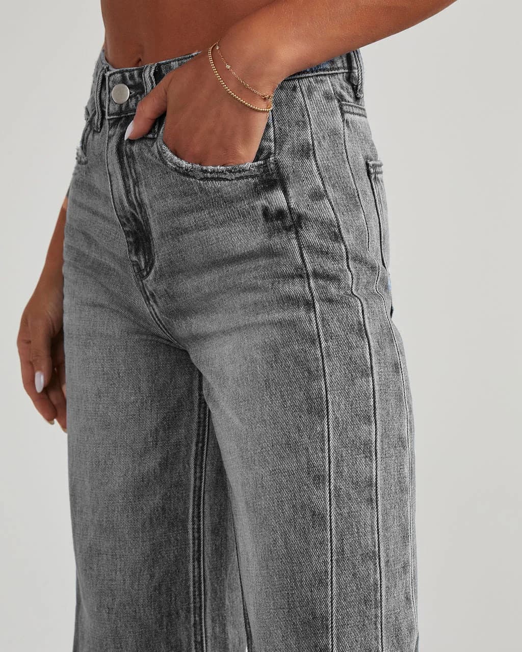 Close-up of high-waist wide-leg grey jeans worn by a person with a hand in the pocket