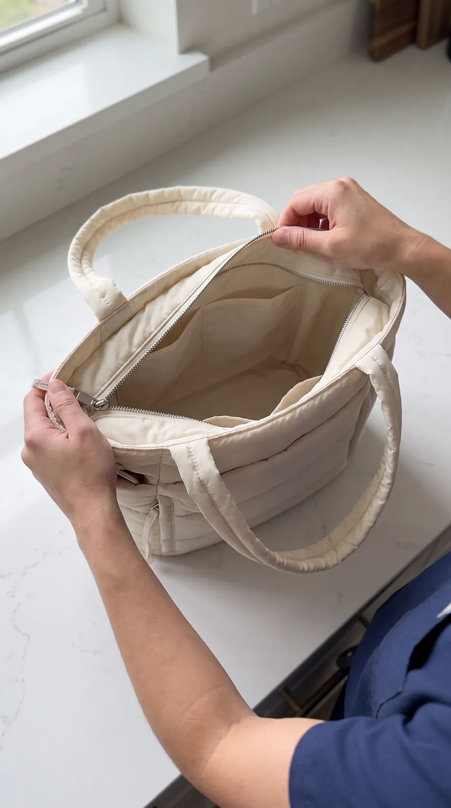 The tote held open to show the wide main opening and the interior slip pockets