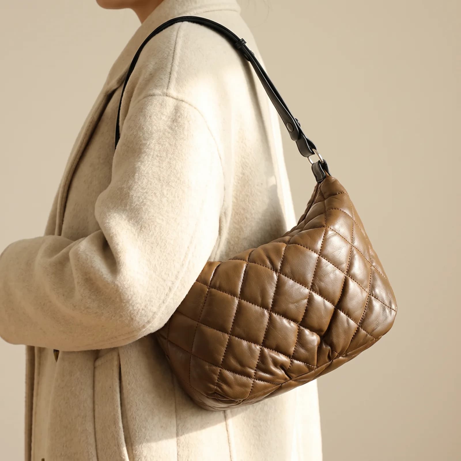 A crossbody bag worn over the shoulder against a coat, no face