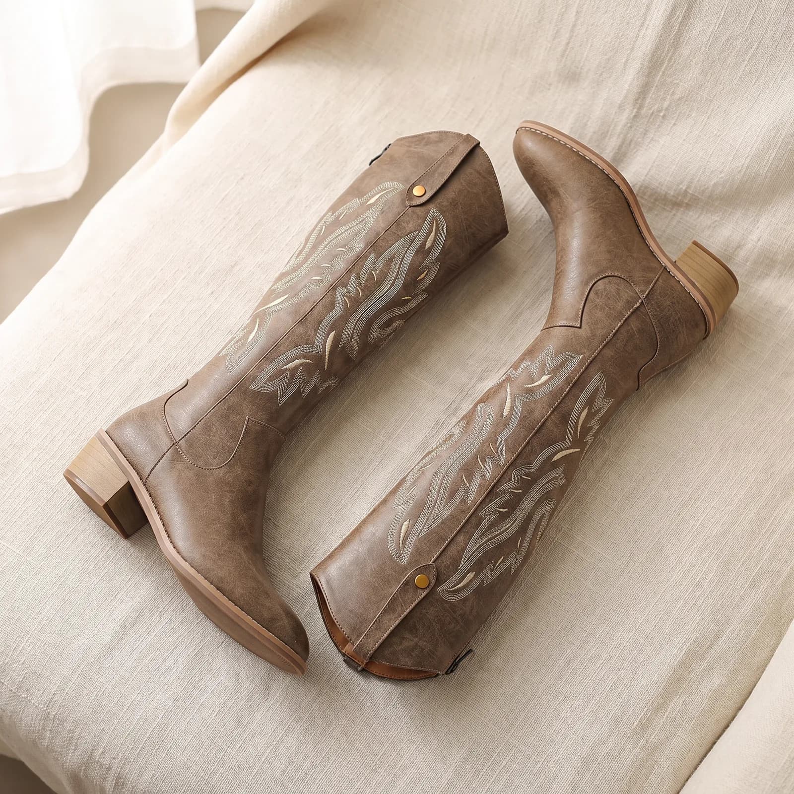 Both boots laid flat top-down on warm cream linen