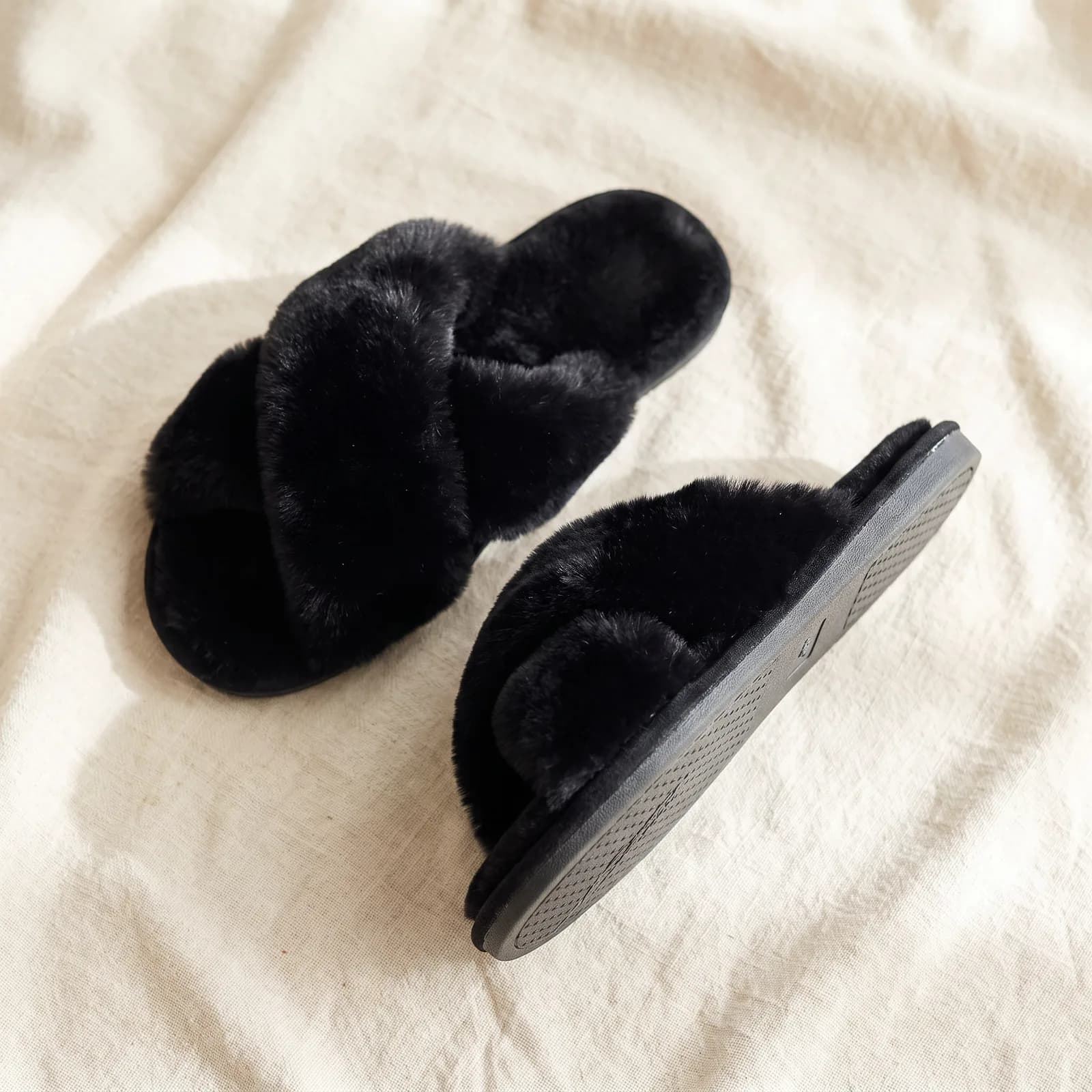 Both slippers laid flat top-down on warm cream linen