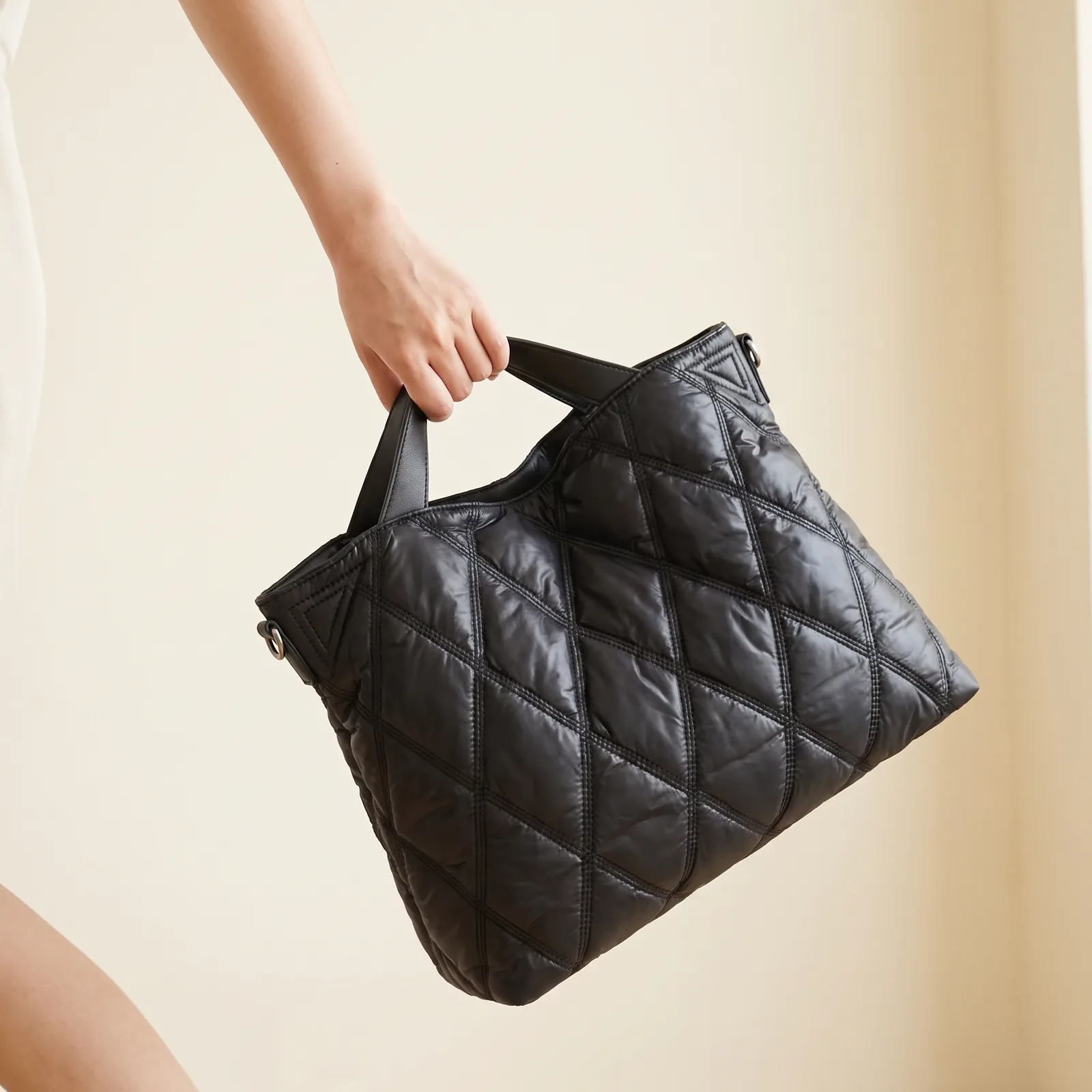 A commuter tote carried by its top handles at hip height, no face