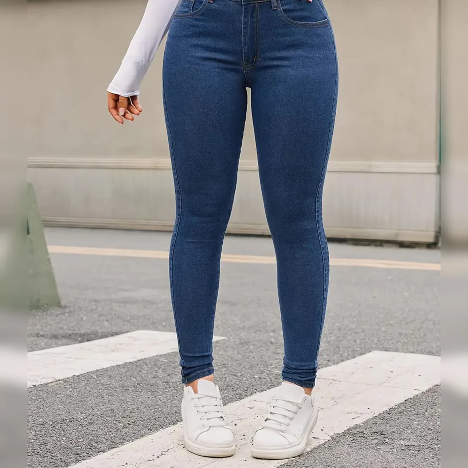 The Medium Wash skinny front on, hands at the waistband