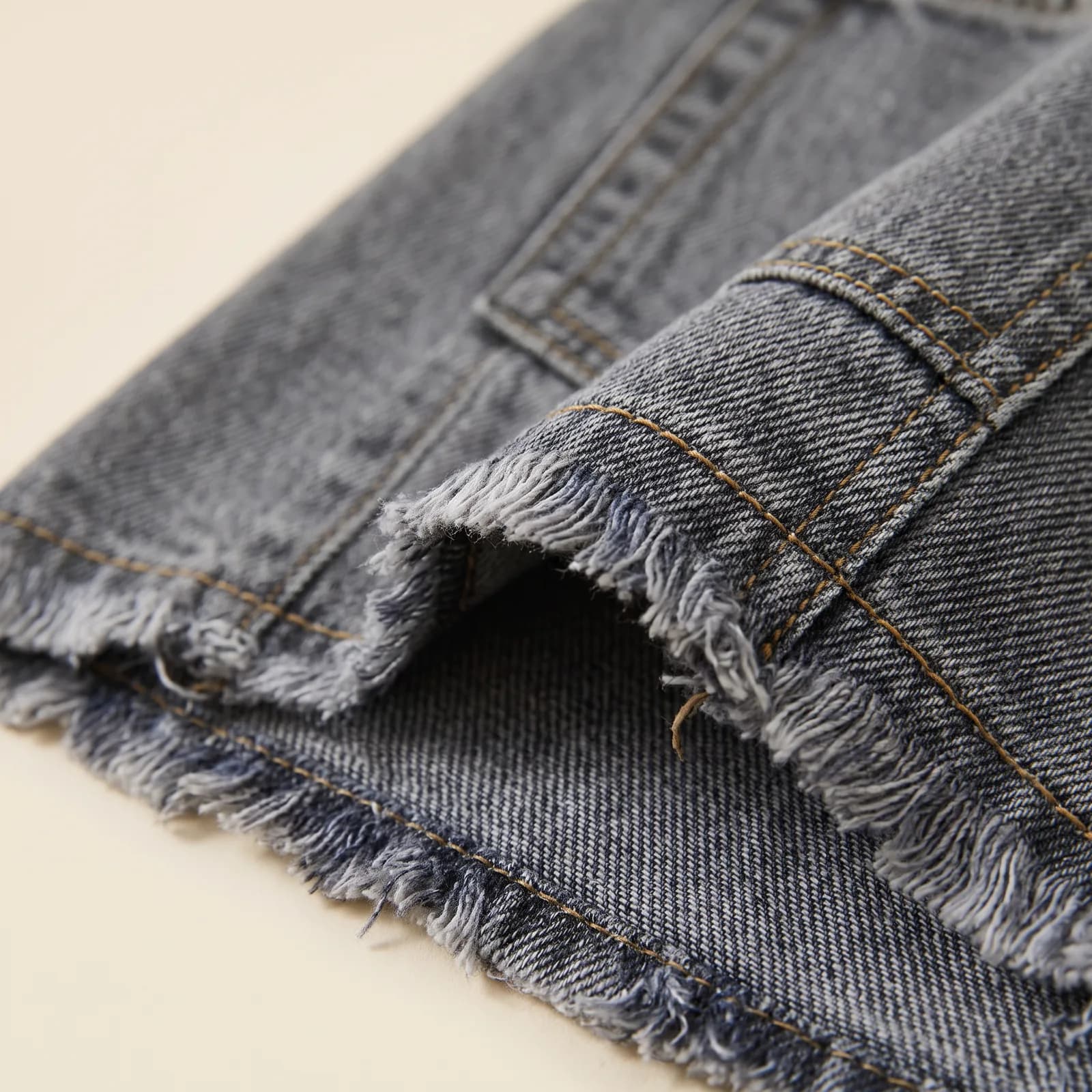 Close-up of the raw frayed hem and back pocket stitching