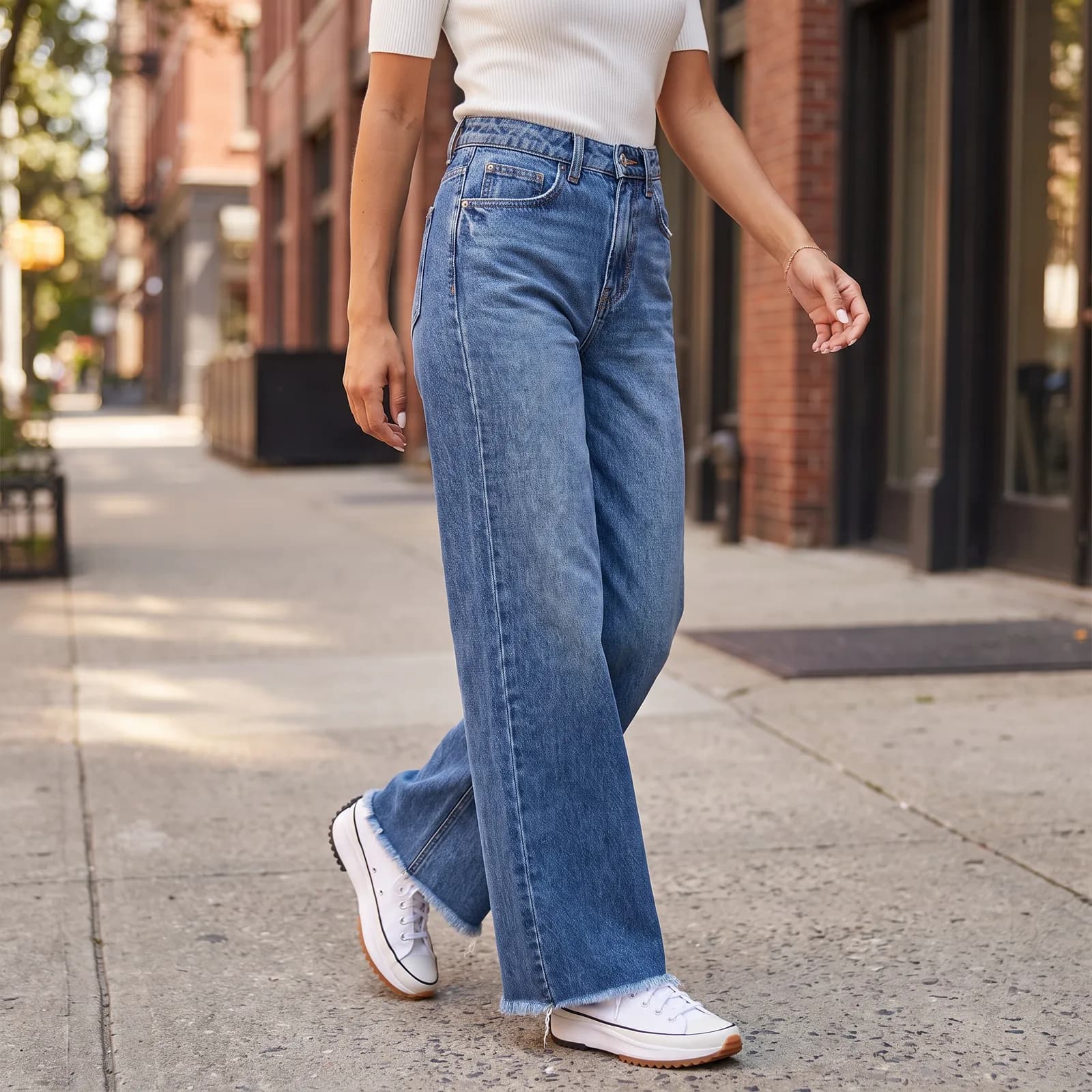 Jeans worn with a simple top, walking on a city sidewalk, no faces