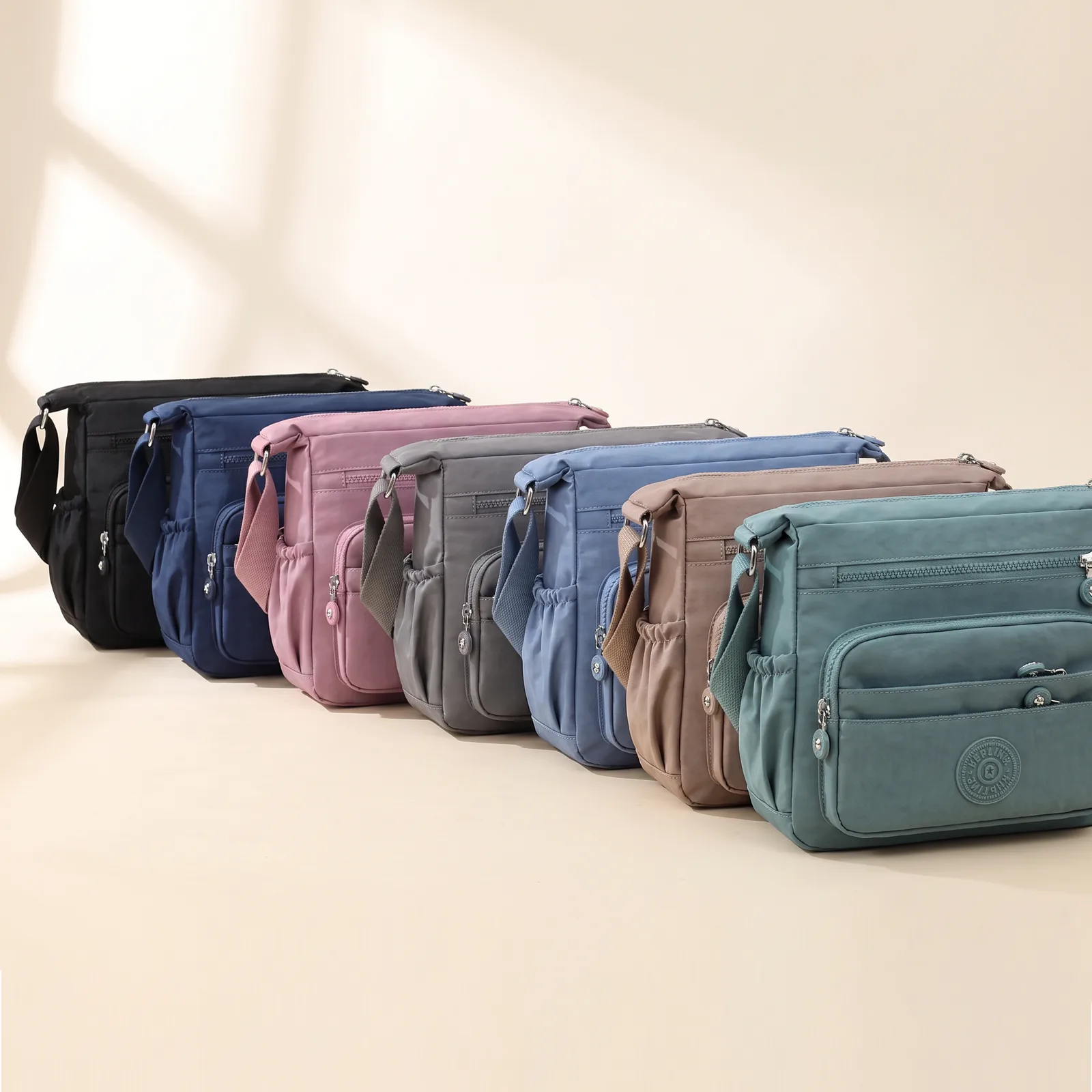 Black, Navy, Plum, Grey, Sky, Latte, and Teal crossbody bags lined up side by side