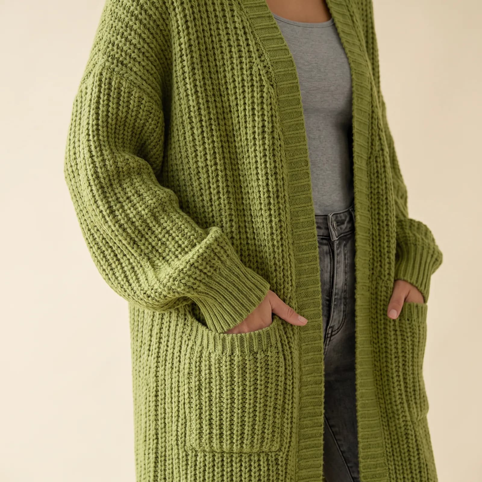 A woman's torso and arms wearing the open cardigan over a top, hands in the pockets