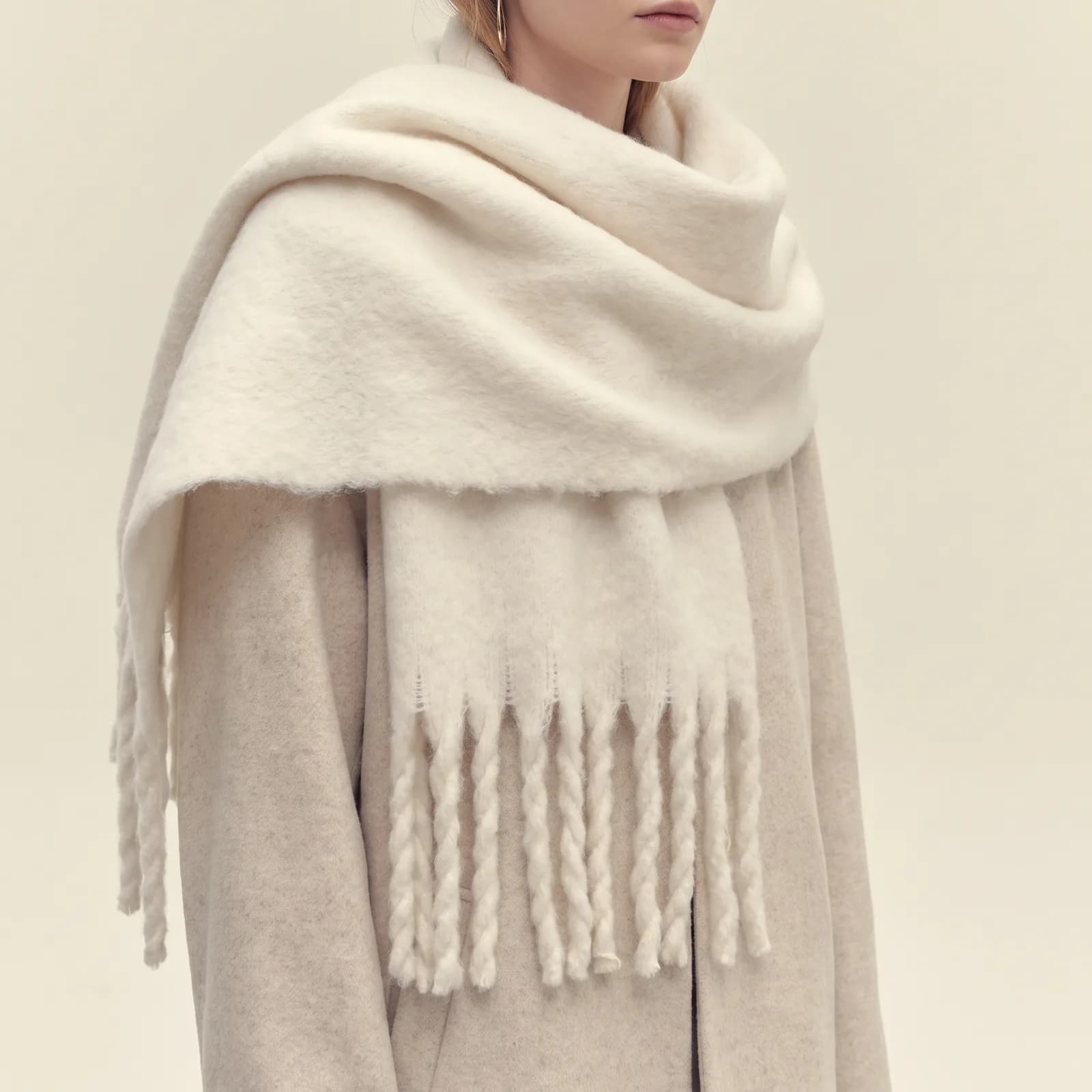 A scarf wrapped loosely as a shawl over a coat, from the shoulders down, no face