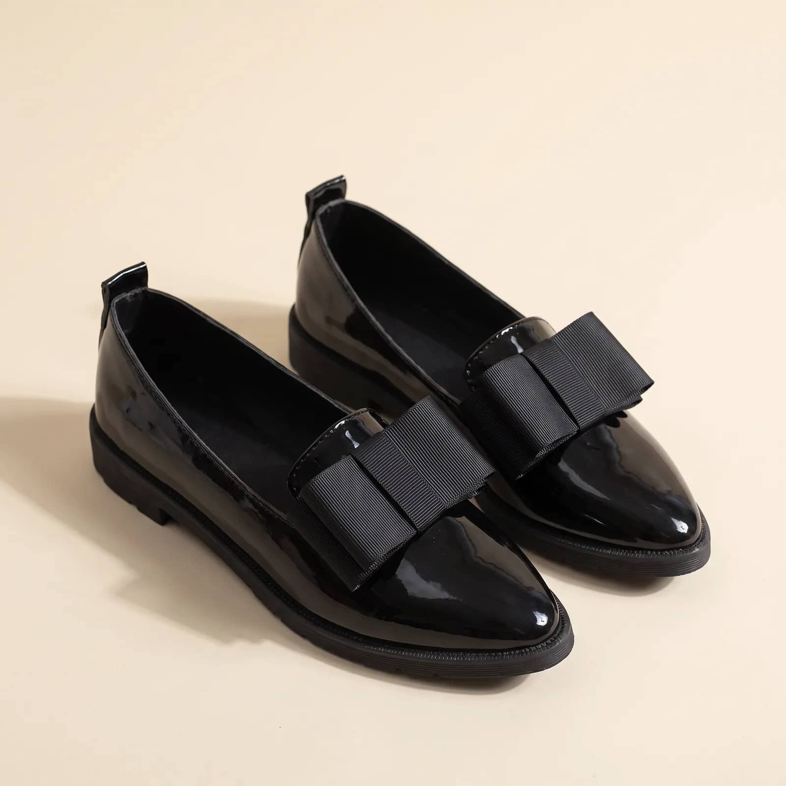Patent Bow Pointed Flats in Black on a cream studio background