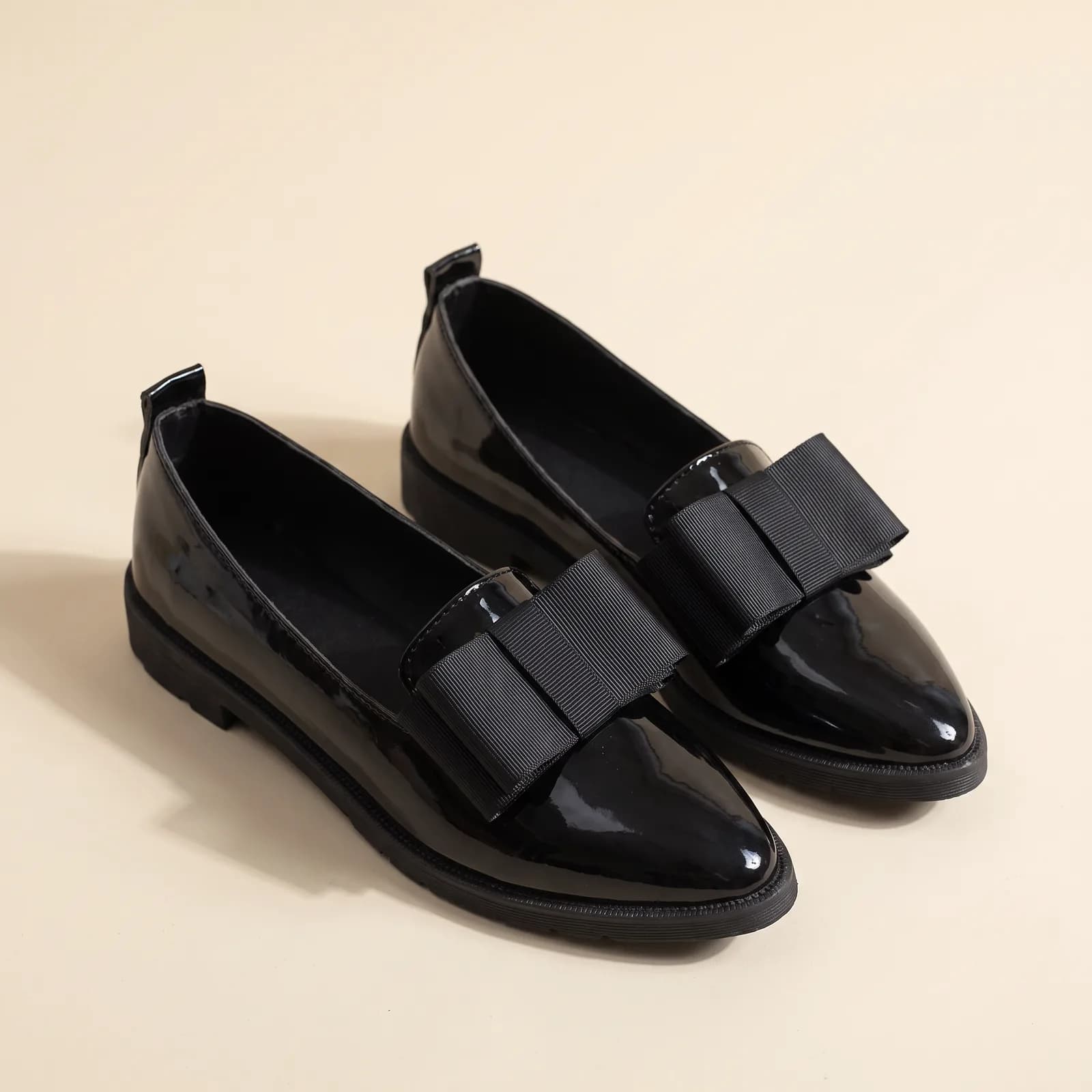 Patent Bow Pointed Flats in Black on a cream studio background