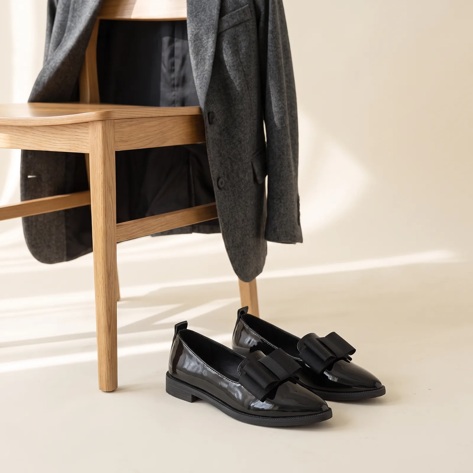 Flats by a chair with a blazer draped over it, no faces