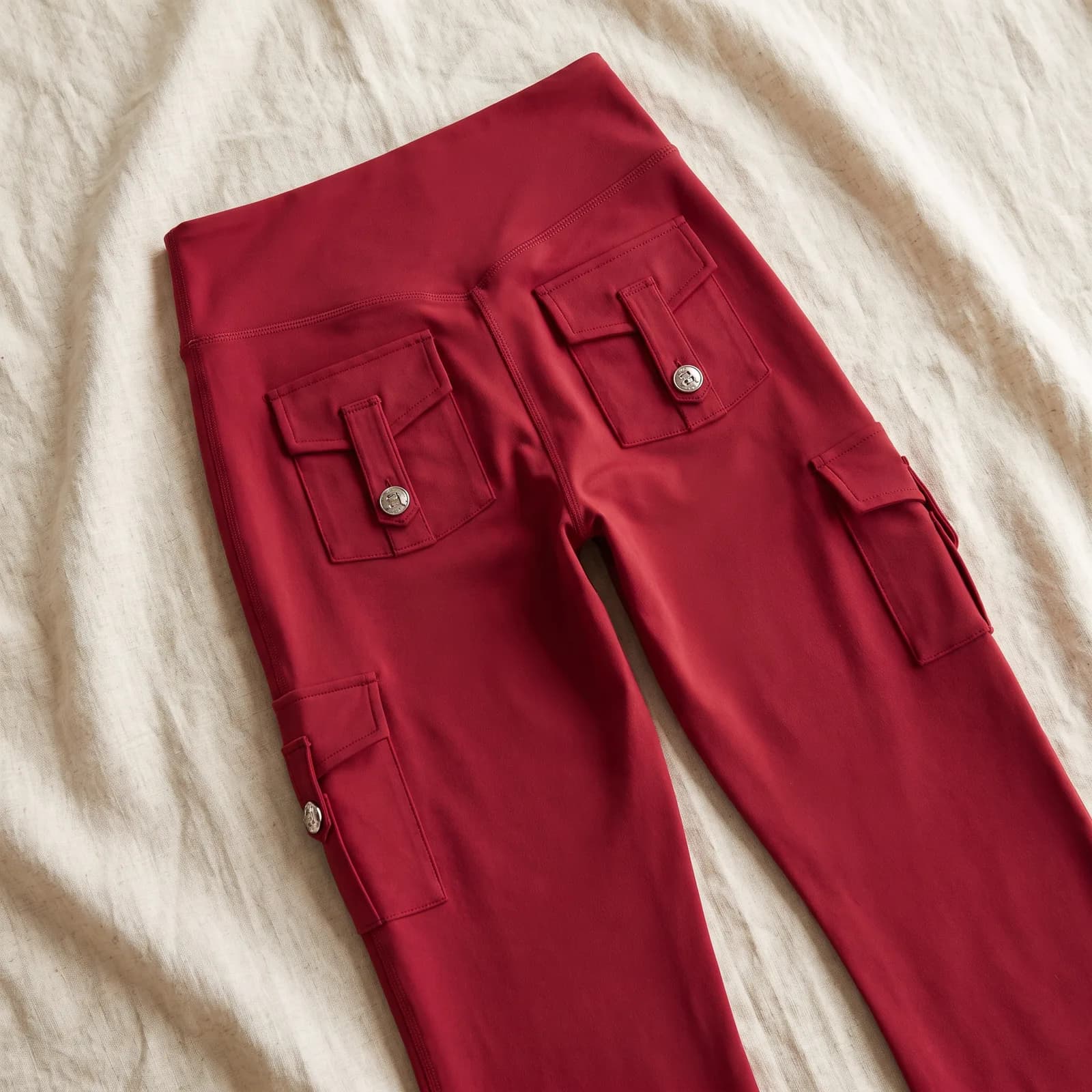 The pants laid flat top-down on warm cream linen, pockets visible