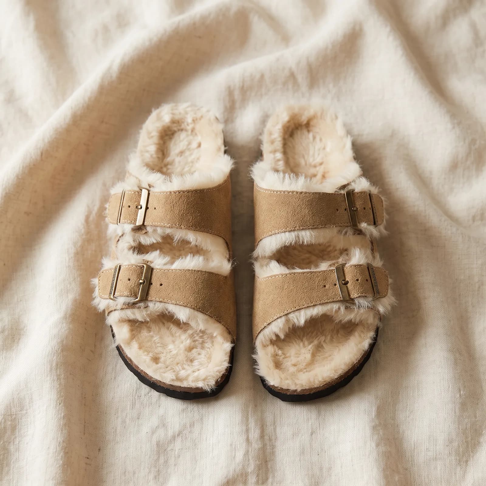 Both clogs laid flat top-down on warm cream linen