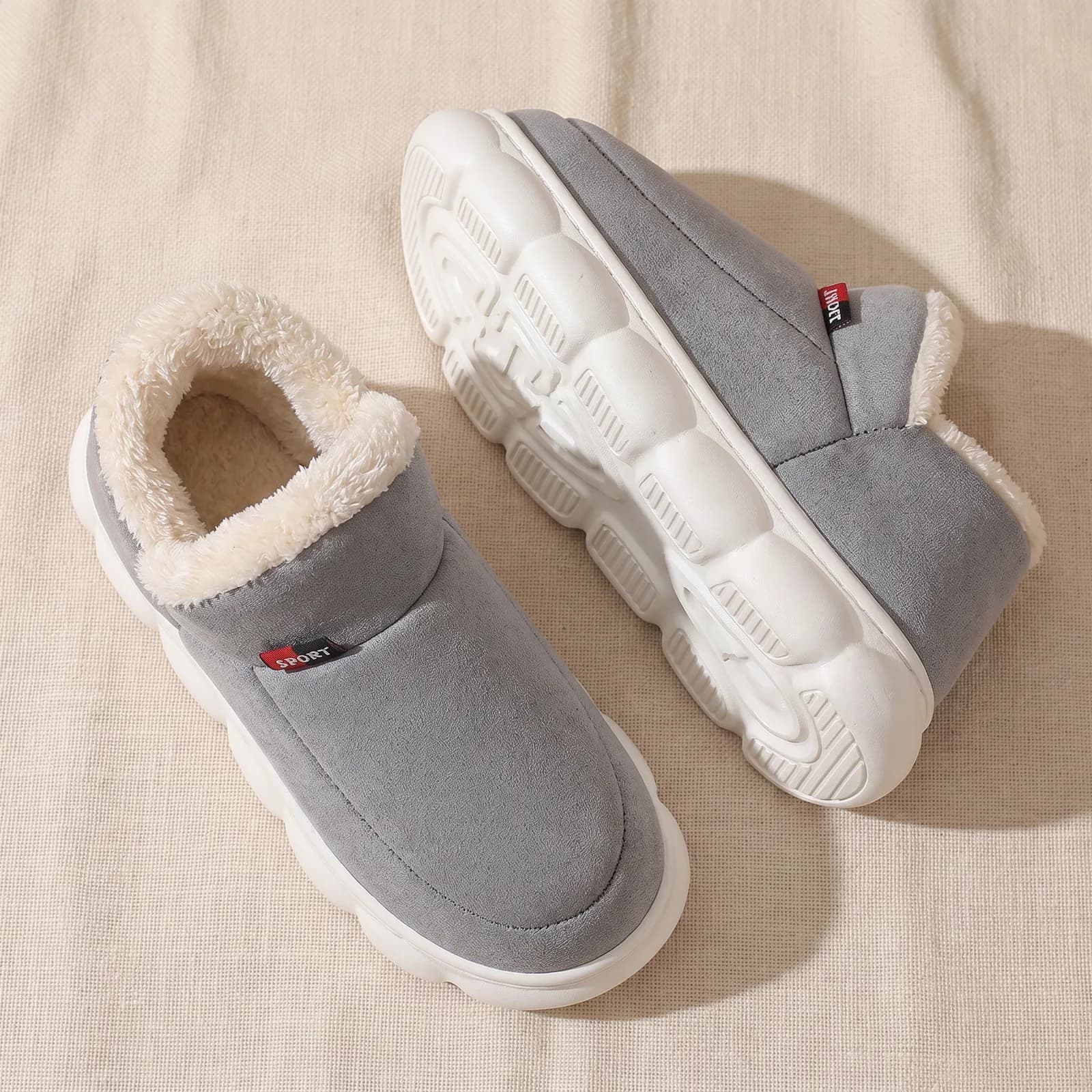 Both booties laid flat top-down on warm cream linen